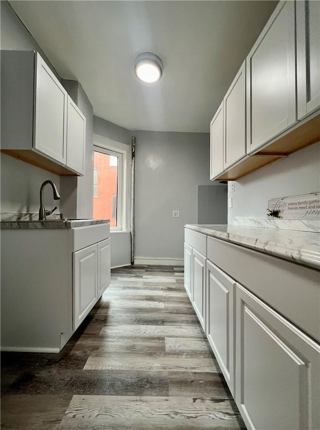 kitchen with light hardwood / wood-style flooring, white cabinets, and sink