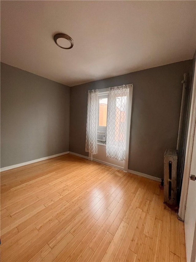 spare room with light hardwood / wood-style floors, radiator, and cooling unit