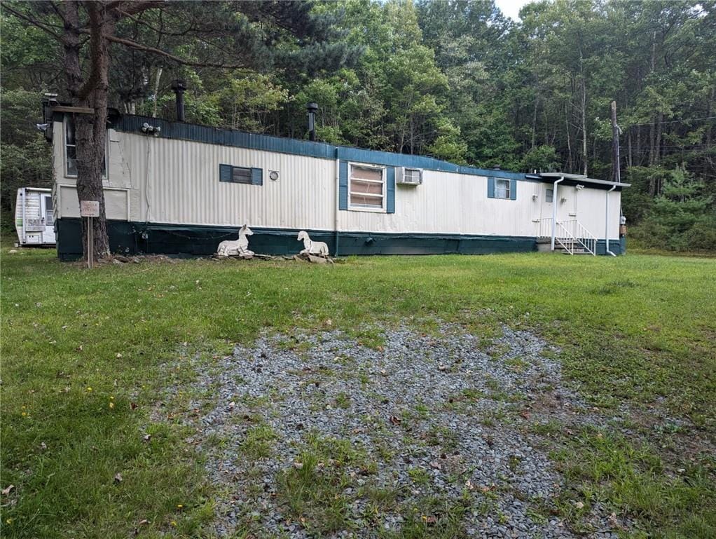 view of property exterior with a wall mounted air conditioner and a yard