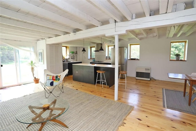 interior space featuring heating unit, beam ceiling, light wood-type flooring, and wooden ceiling