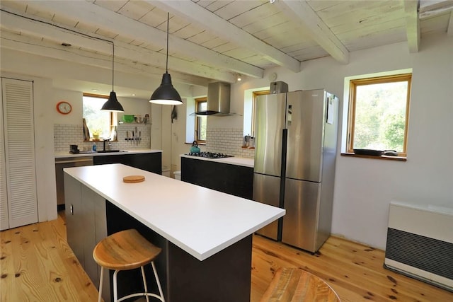 kitchen featuring a wealth of natural light, a center island, wall chimney exhaust hood, and appliances with stainless steel finishes