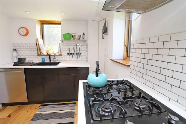 kitchen featuring dark brown cabinetry, dishwasher, sink, decorative backsplash, and light wood-type flooring