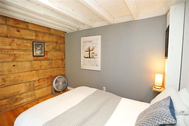 bedroom with wooden walls, beamed ceiling, and wood-type flooring