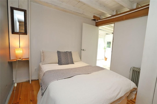 bedroom with radiator heating unit, beamed ceiling, wooden ceiling, and light wood-type flooring