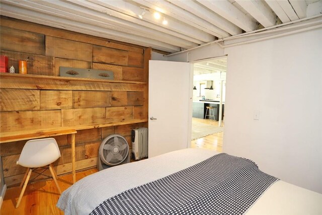 bedroom with wood walls, wood-type flooring, and radiator heating unit