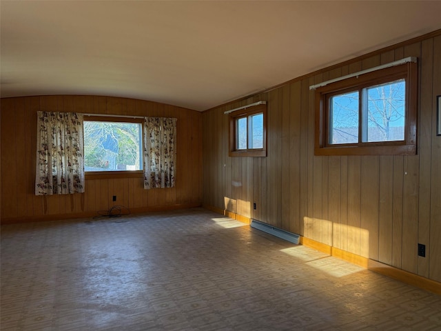 spare room with a baseboard radiator, wooden walls, and vaulted ceiling