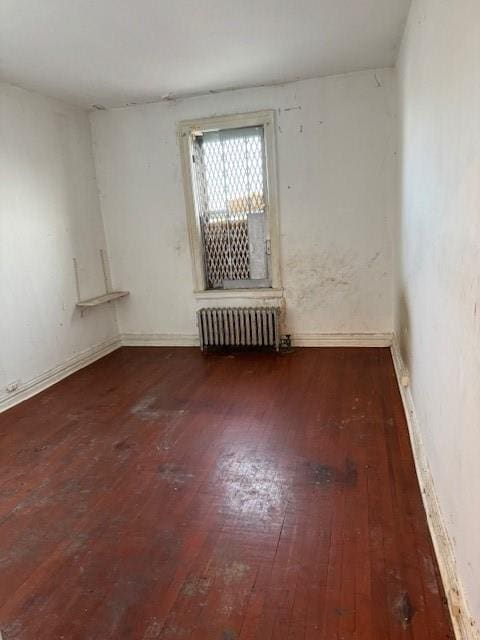 unfurnished room featuring radiator and dark wood-type flooring