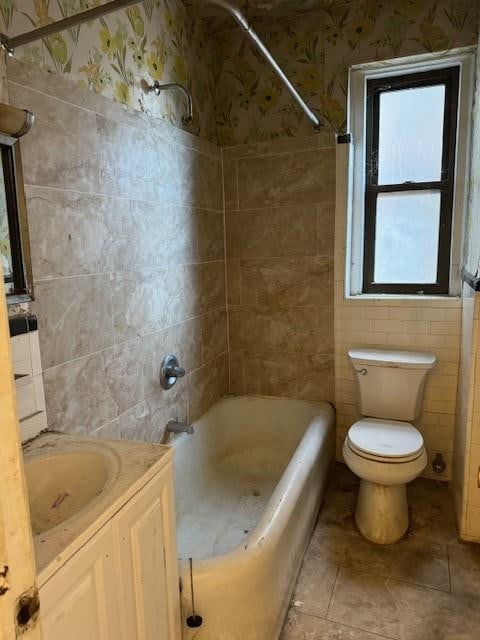 full bathroom with vanity, toilet, tile walls, and tiled shower / bath combo