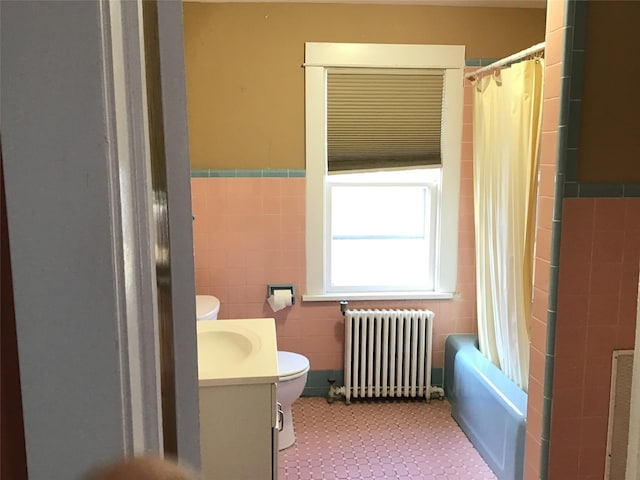 full bathroom featuring vanity, toilet, radiator heating unit, and tile walls