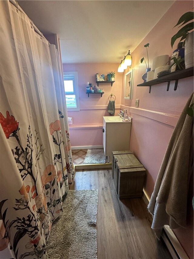 bathroom with baseboard heating, curtained shower, hardwood / wood-style floors, and vanity