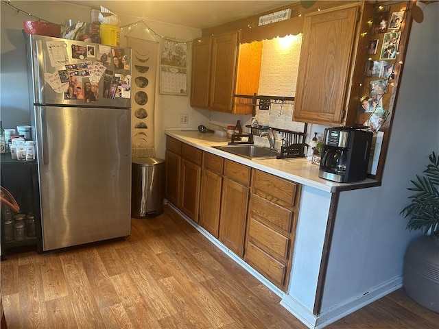 kitchen with stainless steel fridge, sink, and light hardwood / wood-style flooring