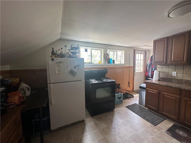 kitchen featuring electric range, white fridge, plenty of natural light, and backsplash