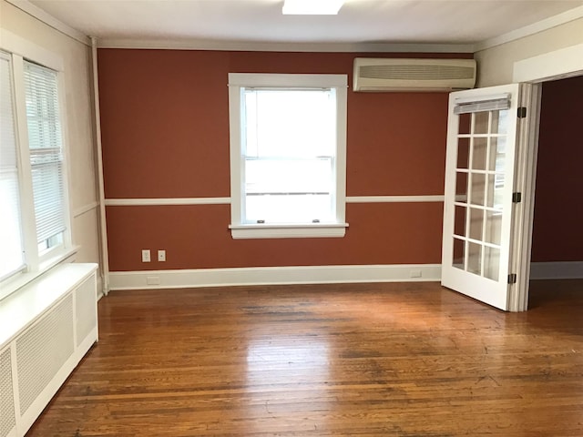 spare room featuring a healthy amount of sunlight, radiator, and a wall unit AC