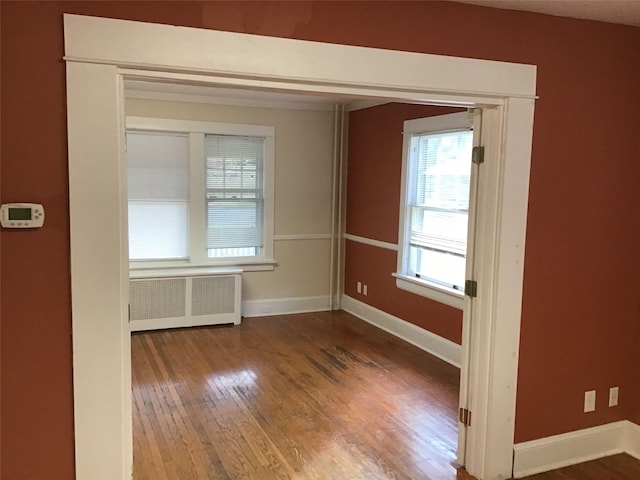 empty room featuring radiator heating unit and hardwood / wood-style flooring