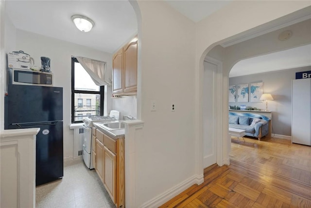 kitchen featuring light brown cabinets, light parquet floors, black fridge, sink, and range