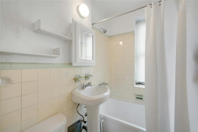 full bathroom with sink, toilet, tile walls, and shower / tub combo with curtain