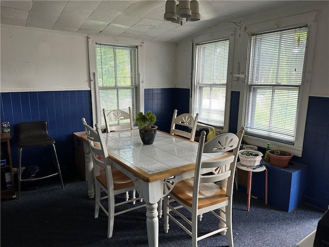 dining space with a wealth of natural light, a notable chandelier, and tile walls