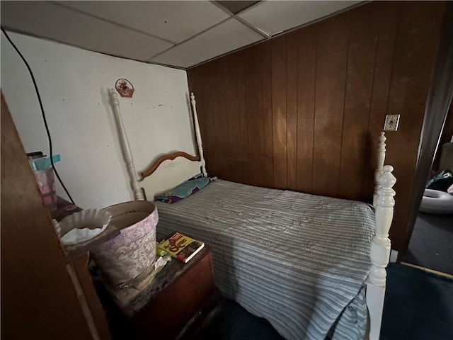 bedroom with a paneled ceiling and wood walls