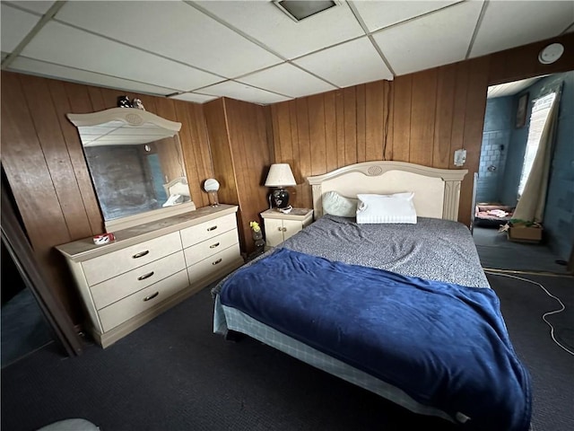 bedroom featuring a paneled ceiling, carpet floors, and wooden walls