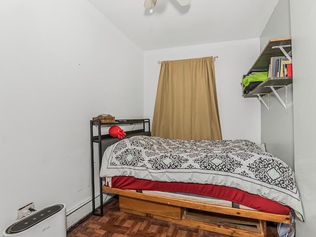 bedroom featuring dark parquet flooring, ceiling fan, and a baseboard heating unit