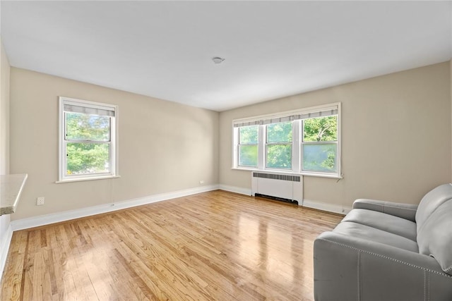 unfurnished living room featuring radiator, light hardwood / wood-style flooring, and a healthy amount of sunlight