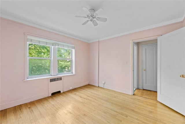 unfurnished room with ceiling fan, light wood-type flooring, and radiator heating unit