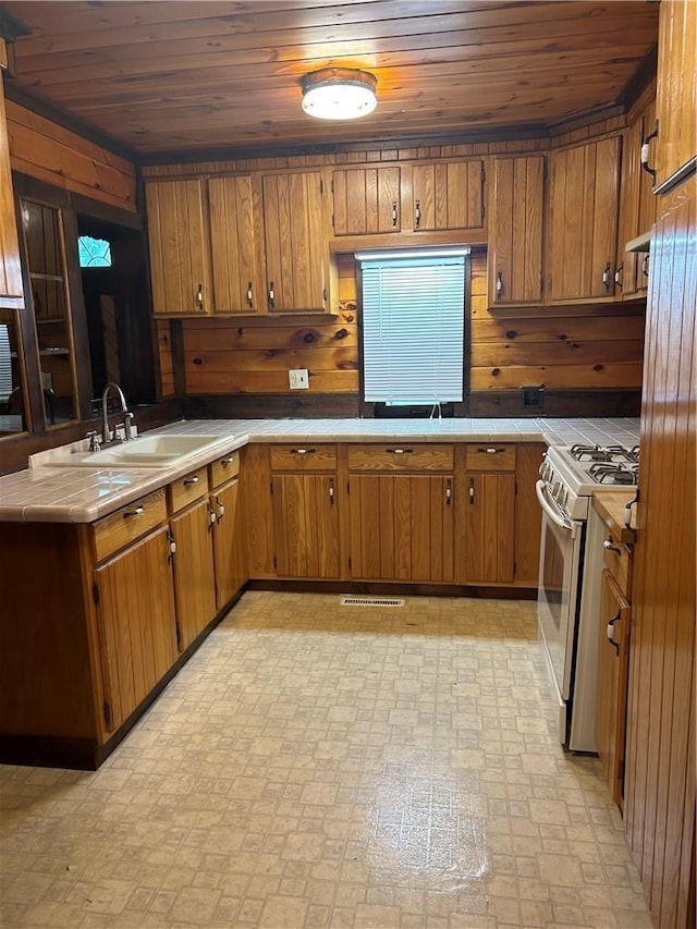 110 Foss Ln, Huguenot, NY 12746 - kitchen featuring white gas stove, wood ceiling, brown cabinetry, tile counters, and wood walls