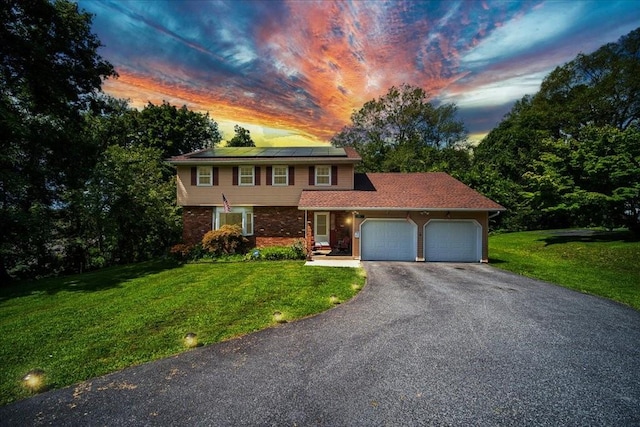 view of front of home with solar panels, a garage, and a yard