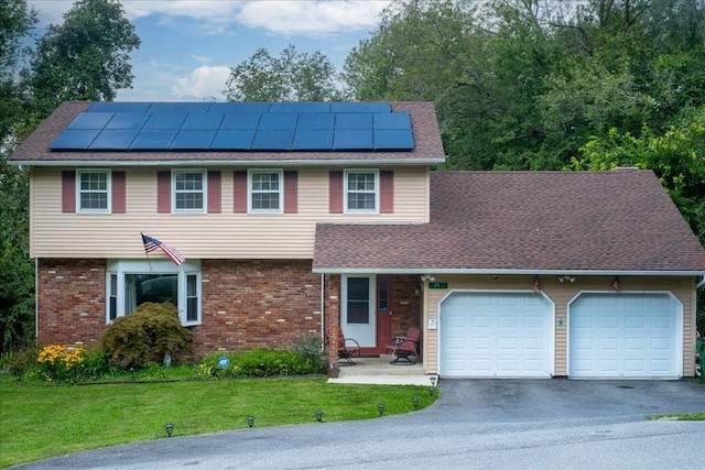 view of front of house featuring solar panels, a garage, and a front lawn