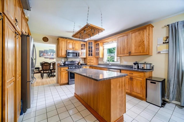 kitchen featuring a center island, sink, dark stone countertops, light tile patterned floors, and stainless steel appliances