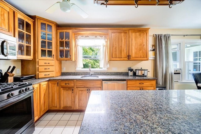 kitchen featuring ceiling fan, sink, dark stone countertops, light tile patterned flooring, and appliances with stainless steel finishes