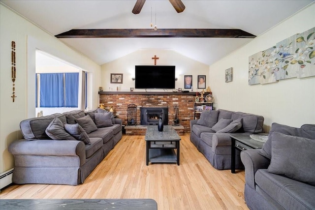 living room featuring vaulted ceiling with beams, light hardwood / wood-style flooring, a wood stove, and ceiling fan