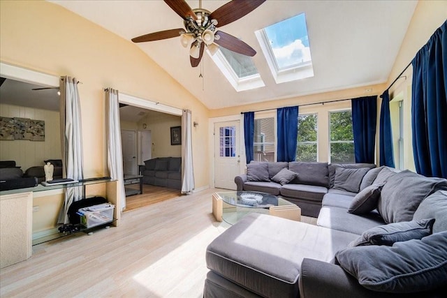 living room with lofted ceiling with skylight, ceiling fan, and light hardwood / wood-style floors