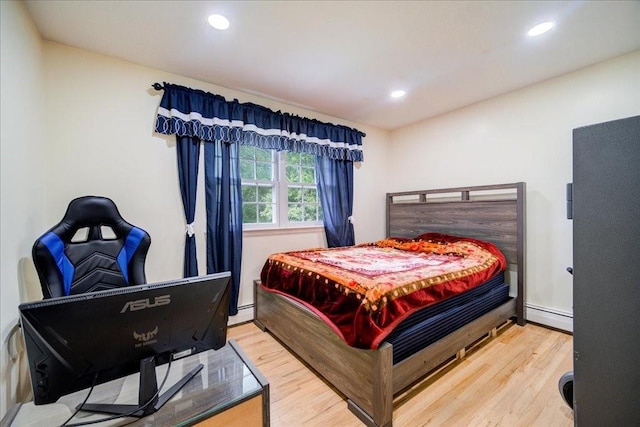 bedroom with hardwood / wood-style floors and a baseboard heating unit