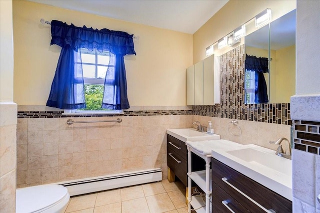 bathroom featuring tile patterned flooring, a baseboard heating unit, toilet, vanity, and tile walls