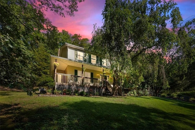 back house at dusk featuring a lawn