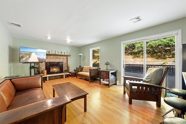 living room featuring light wood-type flooring, a fireplace, and a wealth of natural light