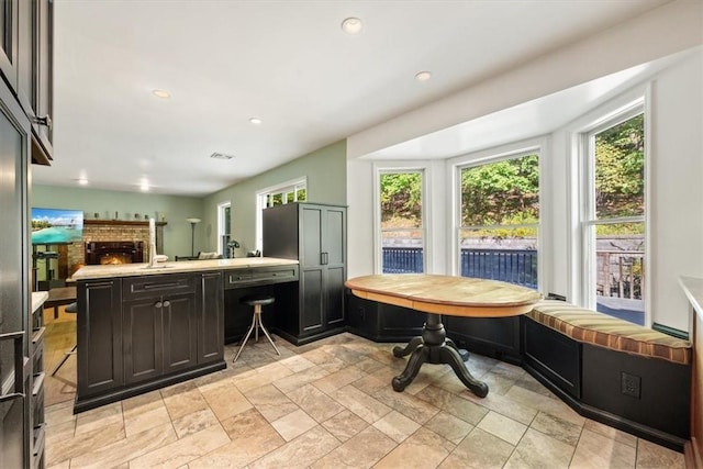 kitchen featuring kitchen peninsula, breakfast area, a wealth of natural light, and a fireplace