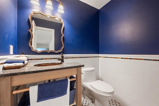 bathroom with toilet, tile patterned floors, tile walls, and sink