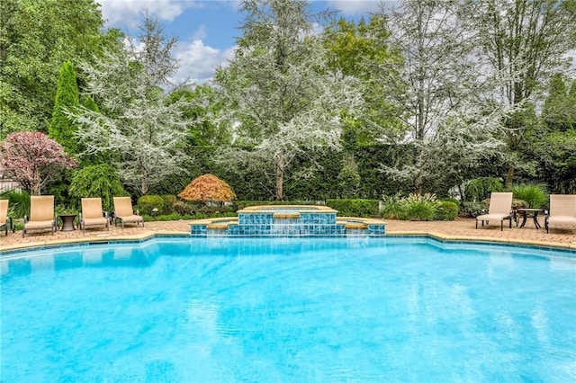 view of swimming pool featuring a patio area and an in ground hot tub