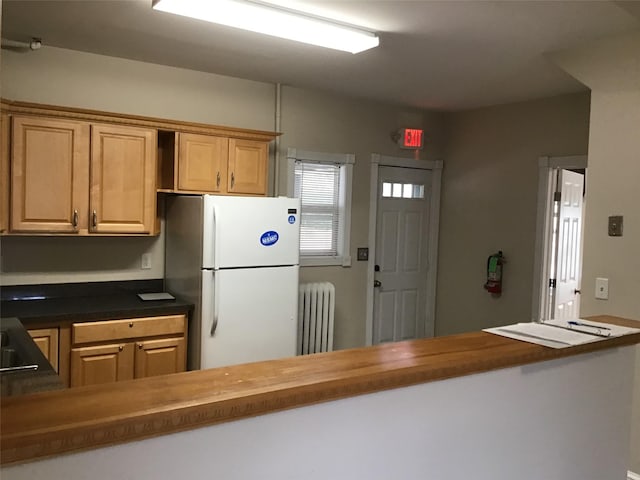 kitchen with wood counters, white fridge, and radiator