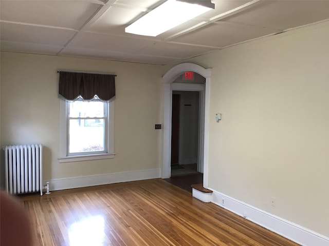 spare room with radiator heating unit and wood-type flooring