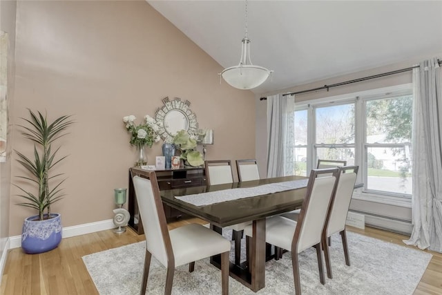 dining area featuring baseboard heating, light hardwood / wood-style floors, and lofted ceiling