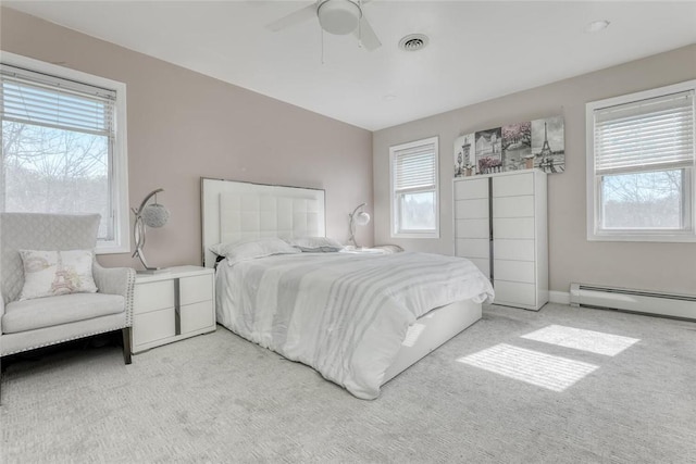 bedroom with ceiling fan, light colored carpet, a baseboard radiator, and multiple windows