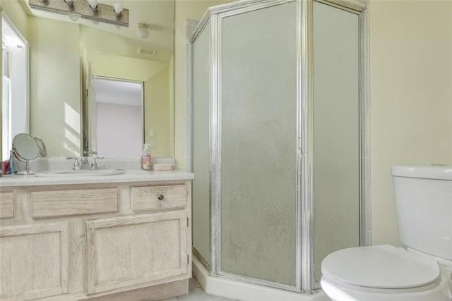 bathroom featuring vanity, toilet, and an enclosed shower