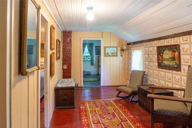 sitting room featuring wood walls, dark wood-type flooring, and vaulted ceiling