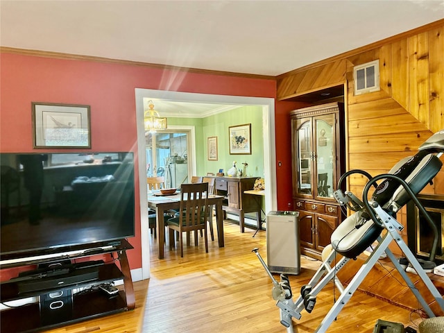 exercise room featuring light hardwood / wood-style floors, baseboard heating, and crown molding