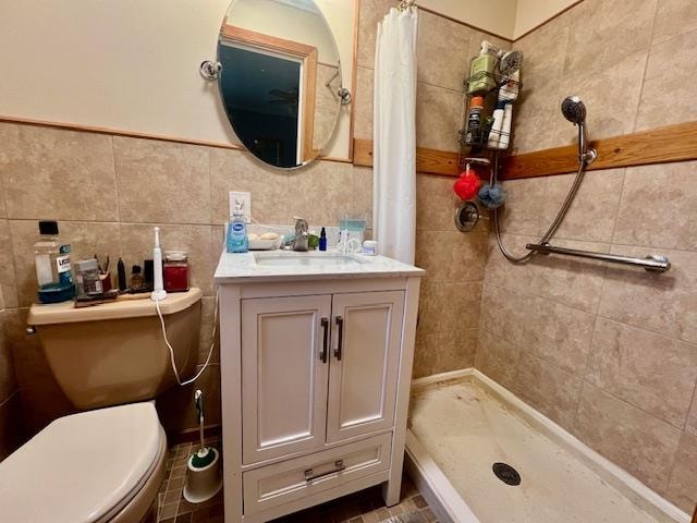 bathroom with toilet, vanity, tile walls, and walk in shower