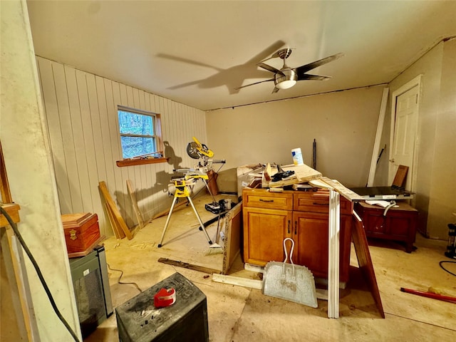 misc room with ceiling fan and wooden walls
