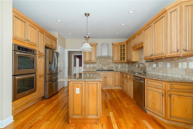 kitchen featuring light hardwood / wood-style flooring, wall chimney exhaust hood, decorative light fixtures, a kitchen island, and stainless steel appliances